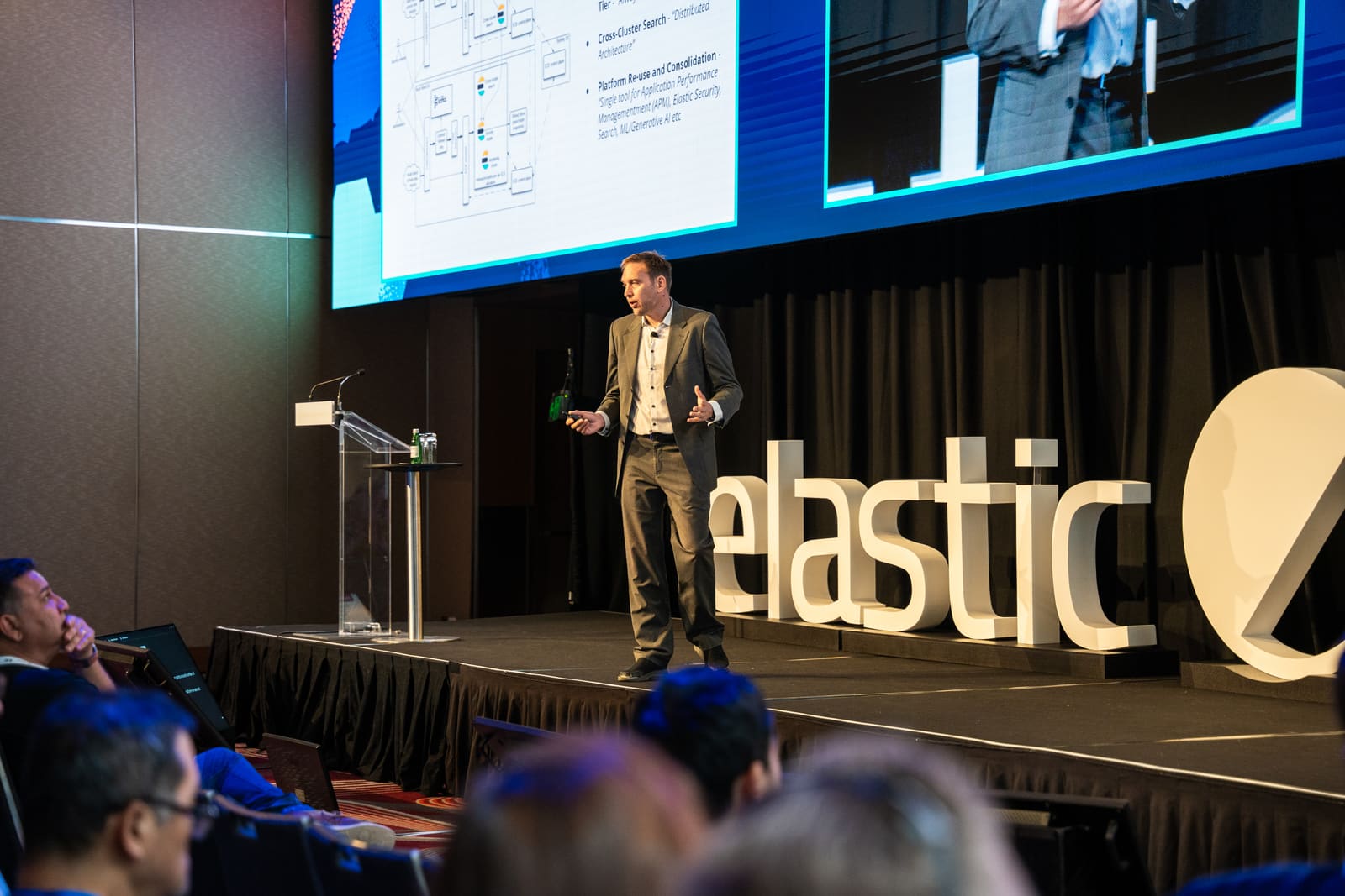 Clayton Hubbard presenting national-scale platform architecture on stage at an Elastic conference